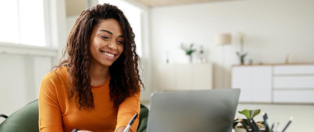 Smiling student in front of laptop representing the new online Counseling programs and online OTD program at American International College