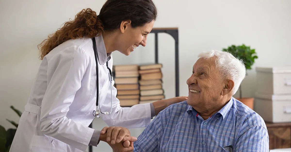 A nurse puts a hand on an older patient’s shoulder.