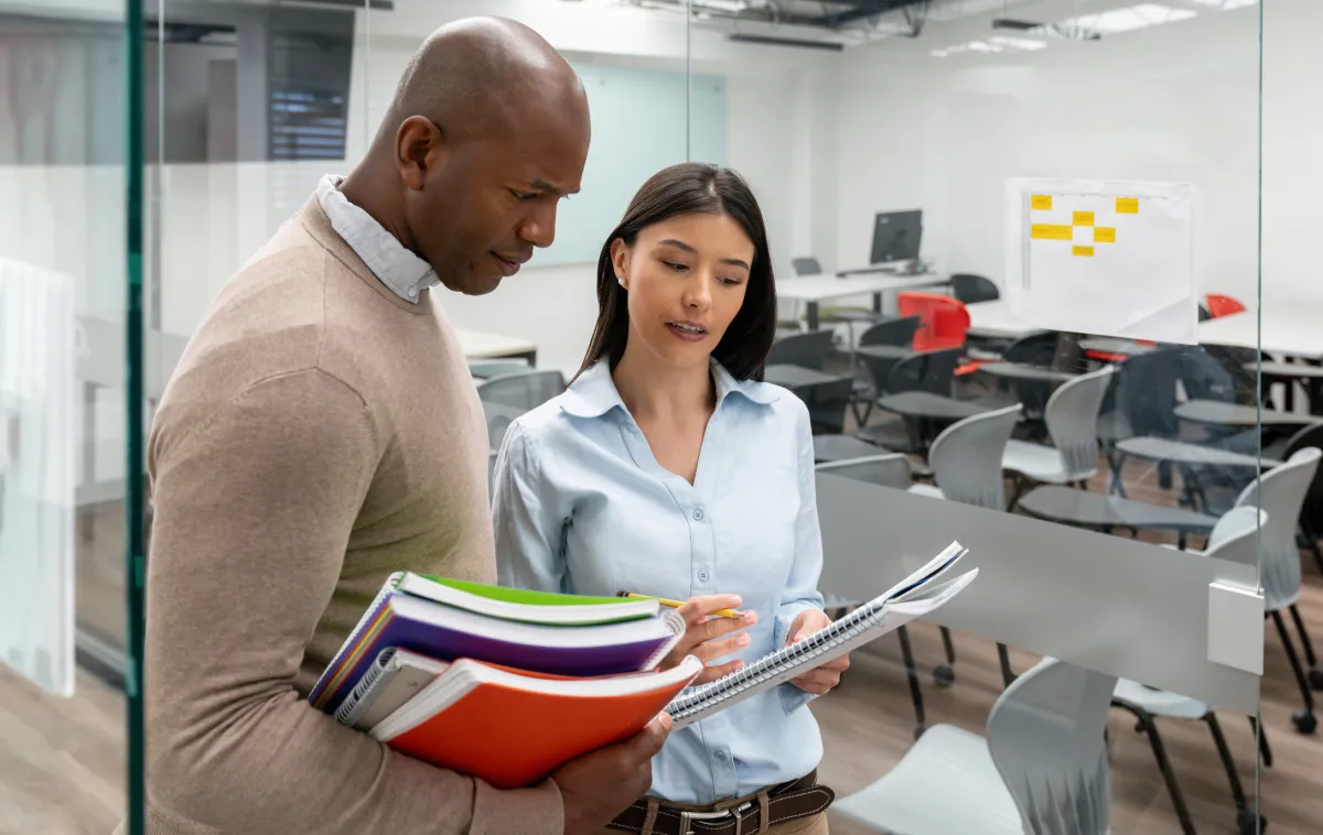 A mentor teacher gives advice to a colleague in a college classroom