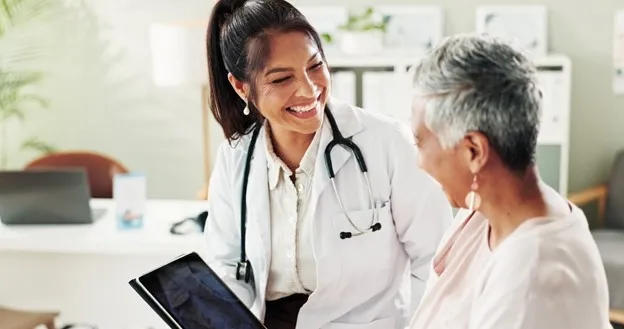 A family nurse practitioner uses a tablet to explain a condition to a patient.