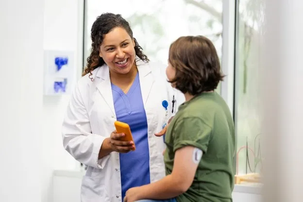 A family nurse practitioner talks with a young patient in an exaA family nurse practitioner talks with a young patient in an examination room.mination room.