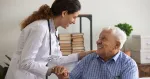 A nurse puts a hand on an older patient’s shoulder.